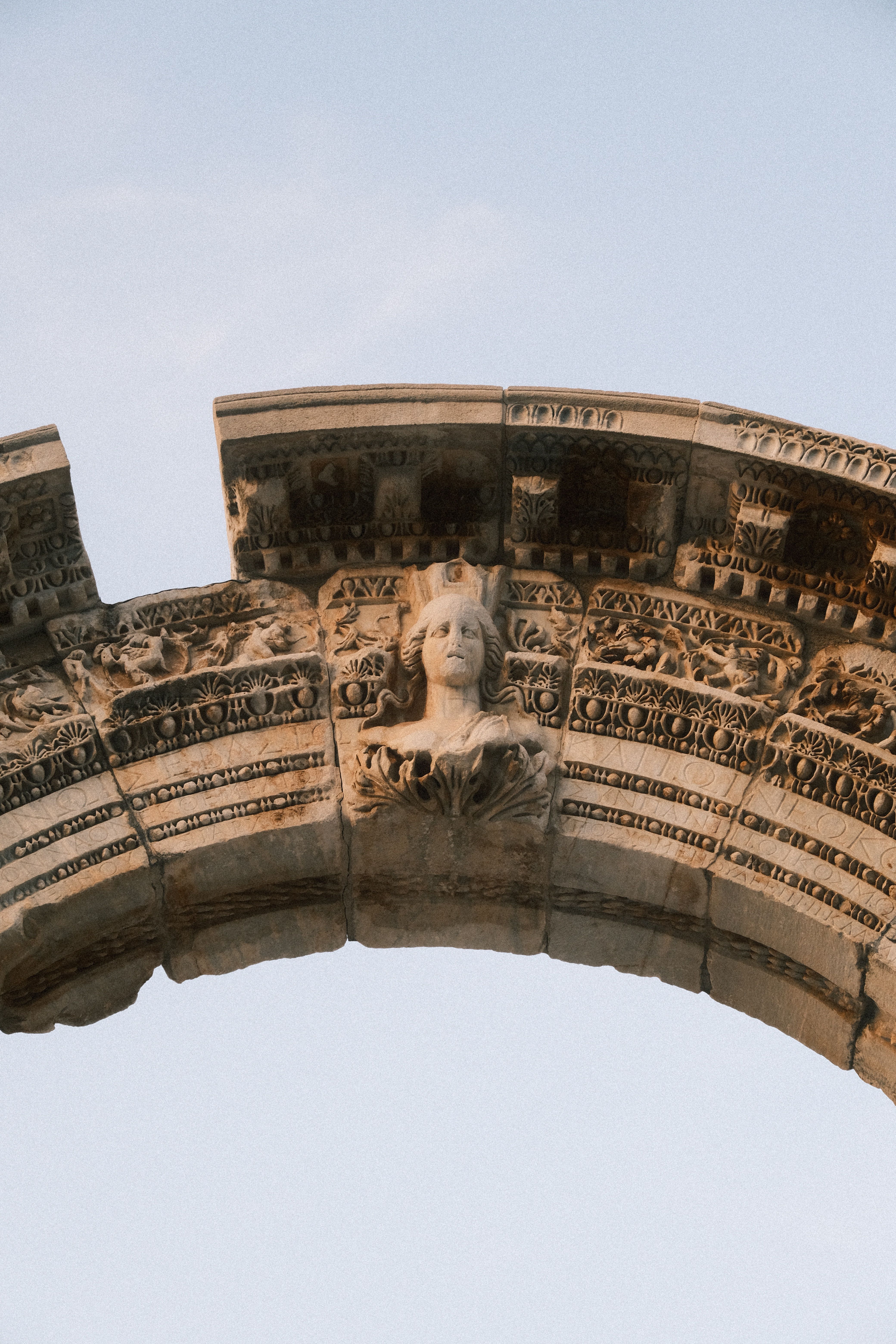 Close-up view of an ancient stone arch featuring intricate sculptures in a historical setting.