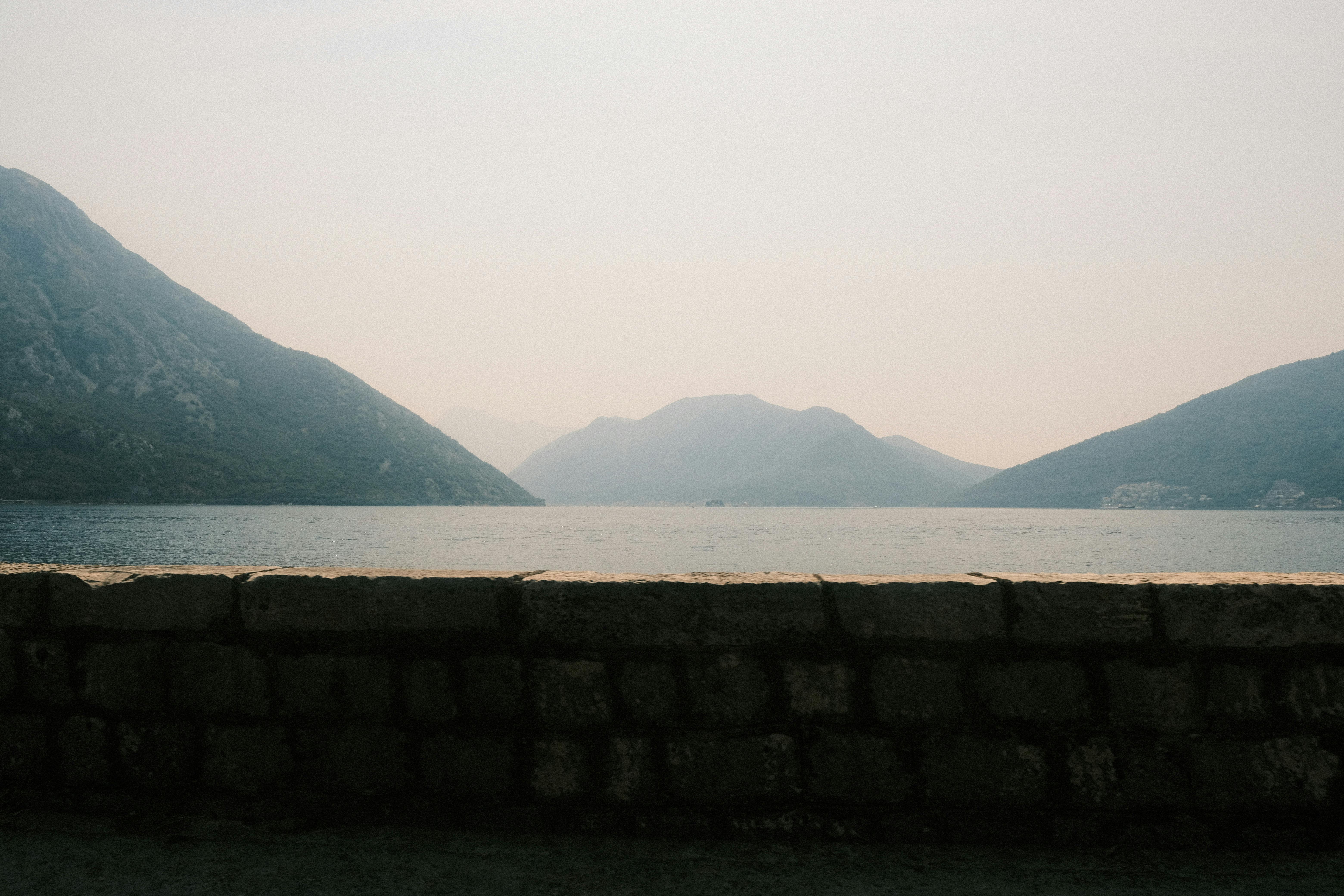 a man is standing on a wall looking out at the water