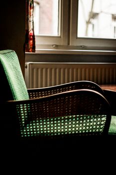 A vintage armchair bathed in warm sunlight near a window, creating a cozy indoor vibe.