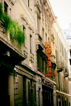 Historic hotel facade on a charming city street with vibrant greenery.