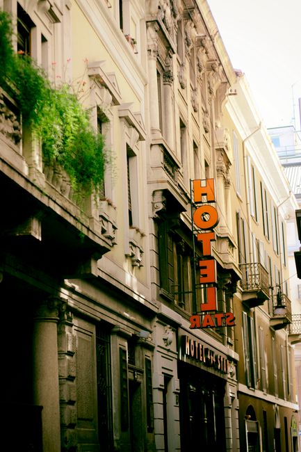 Historic hotel facade on a charming city street with vibrant greenery.