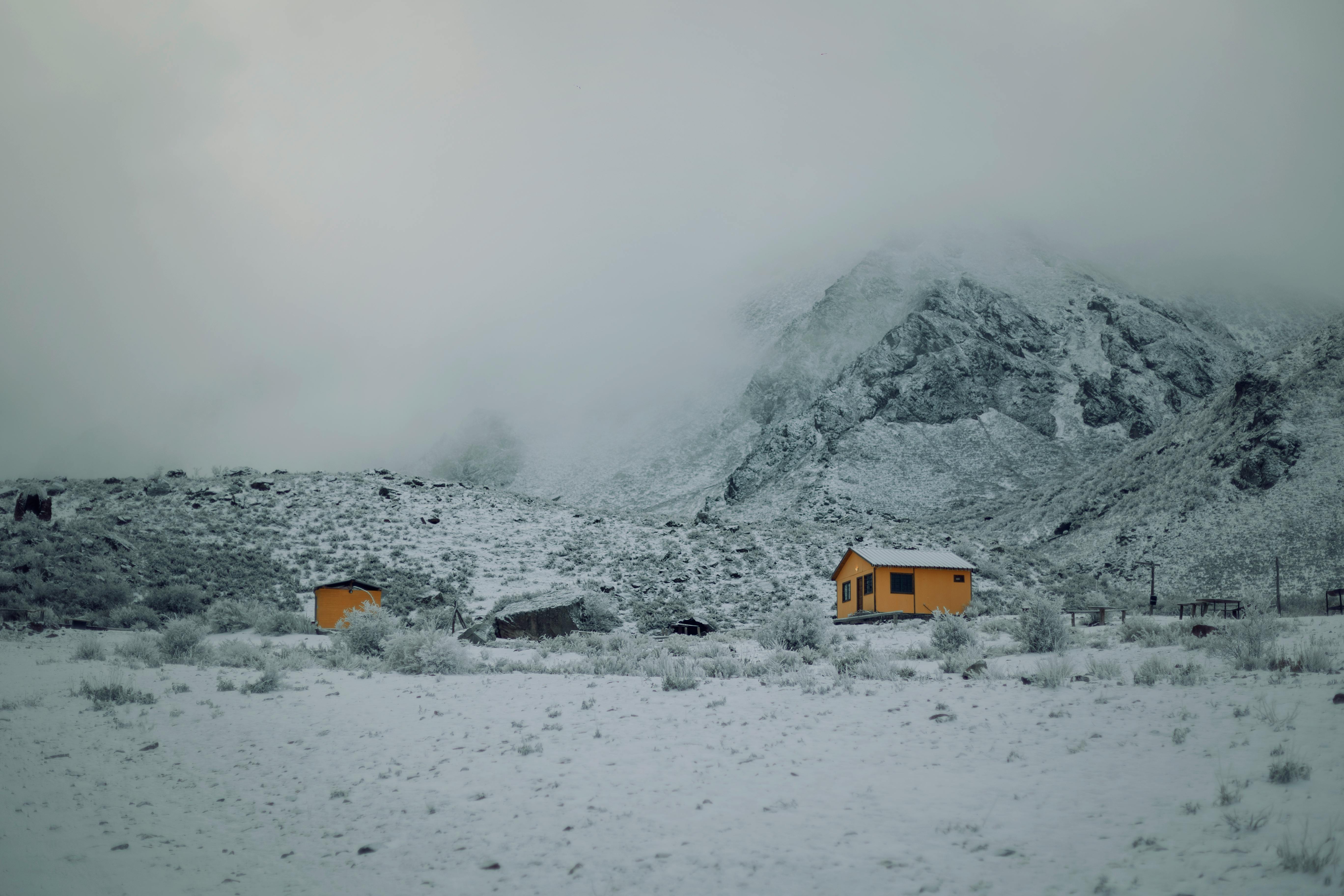 A picturesque snowy landscape with yellow houses nestled in foggy mountains, evoking winter tranquility.