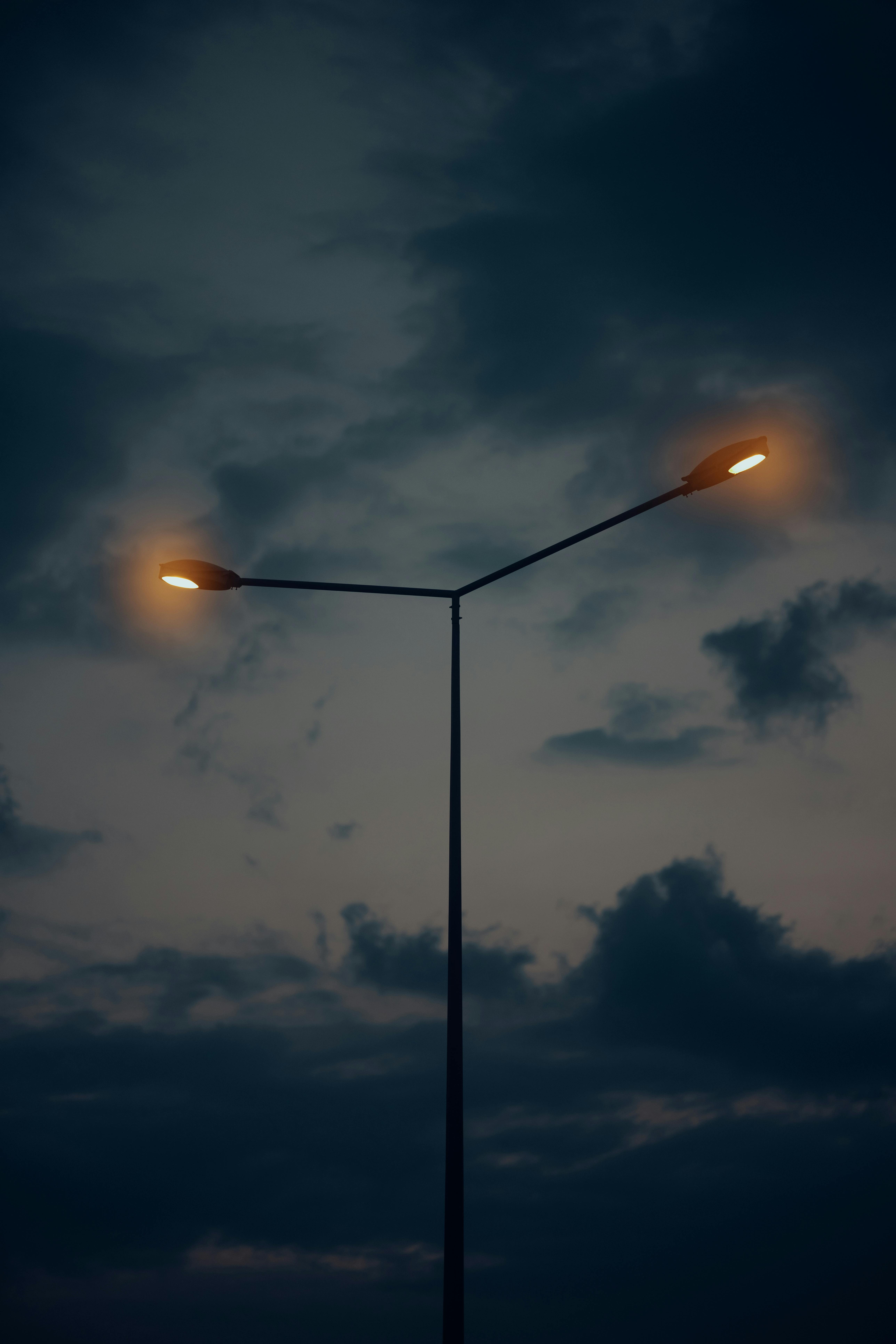 Streetlamp illuminates evening sky with dramatic clouds creating a moody atmosphere.
