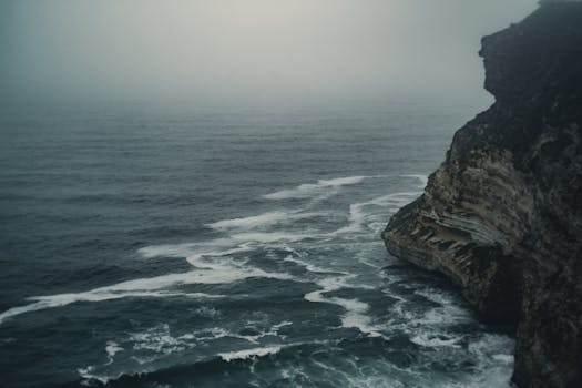 Dark and moody ocean scene with a foggy cliff in Salalah, Oman.