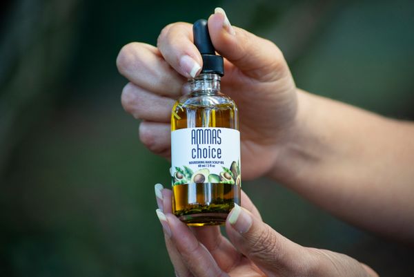 Hand holding a small scalp oil bottle