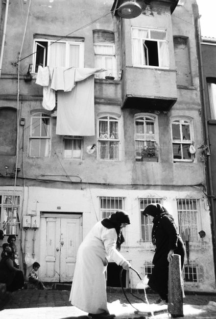 A candid black and white street scene in İstanbul, showcasing cultural life and historic architecture.