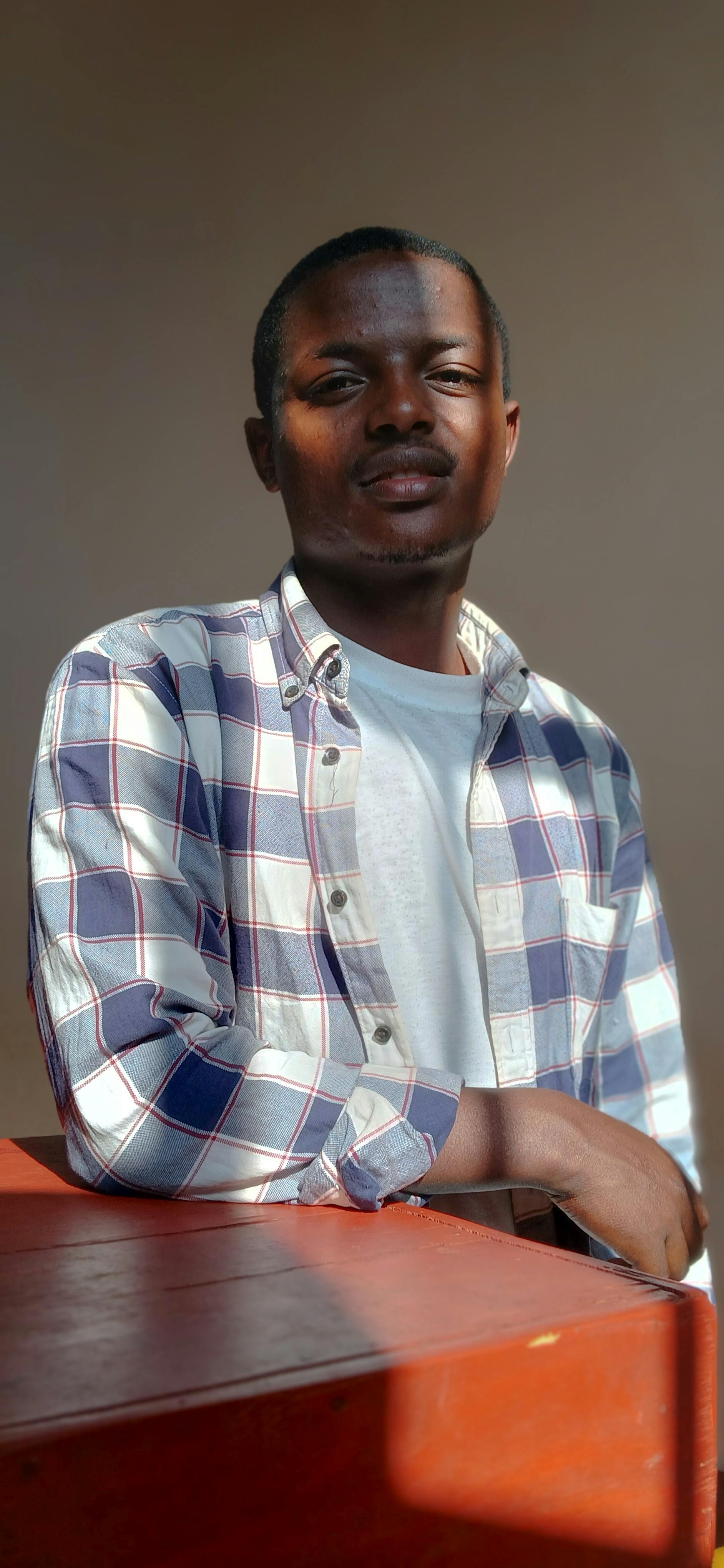 Portrait of a young man in casual attire indoors with natural sunlight casting shadows.