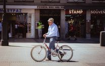 A man walks beside his bicycle in front of shops at Puerta del Sol, Madrid, Spain.