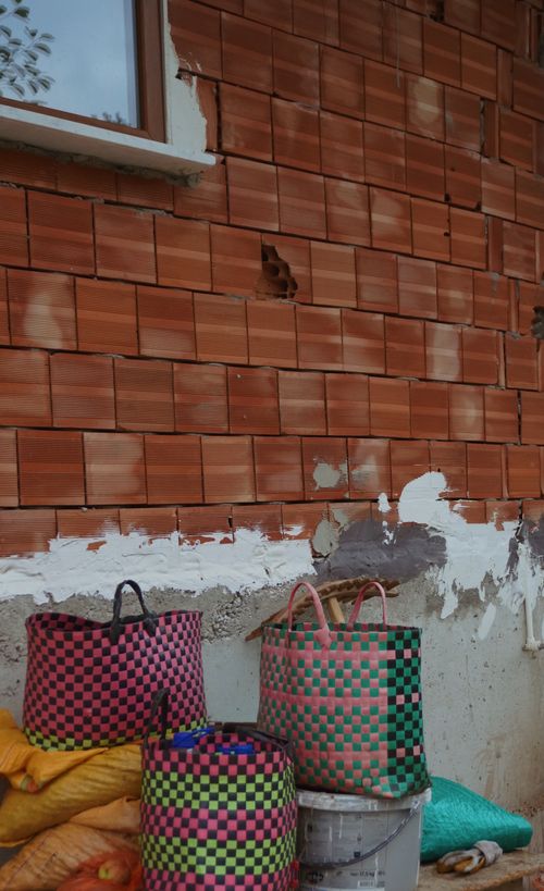 Free Three woven bags against an unfinished brick wall, showcasing texture and color. Stock Photo