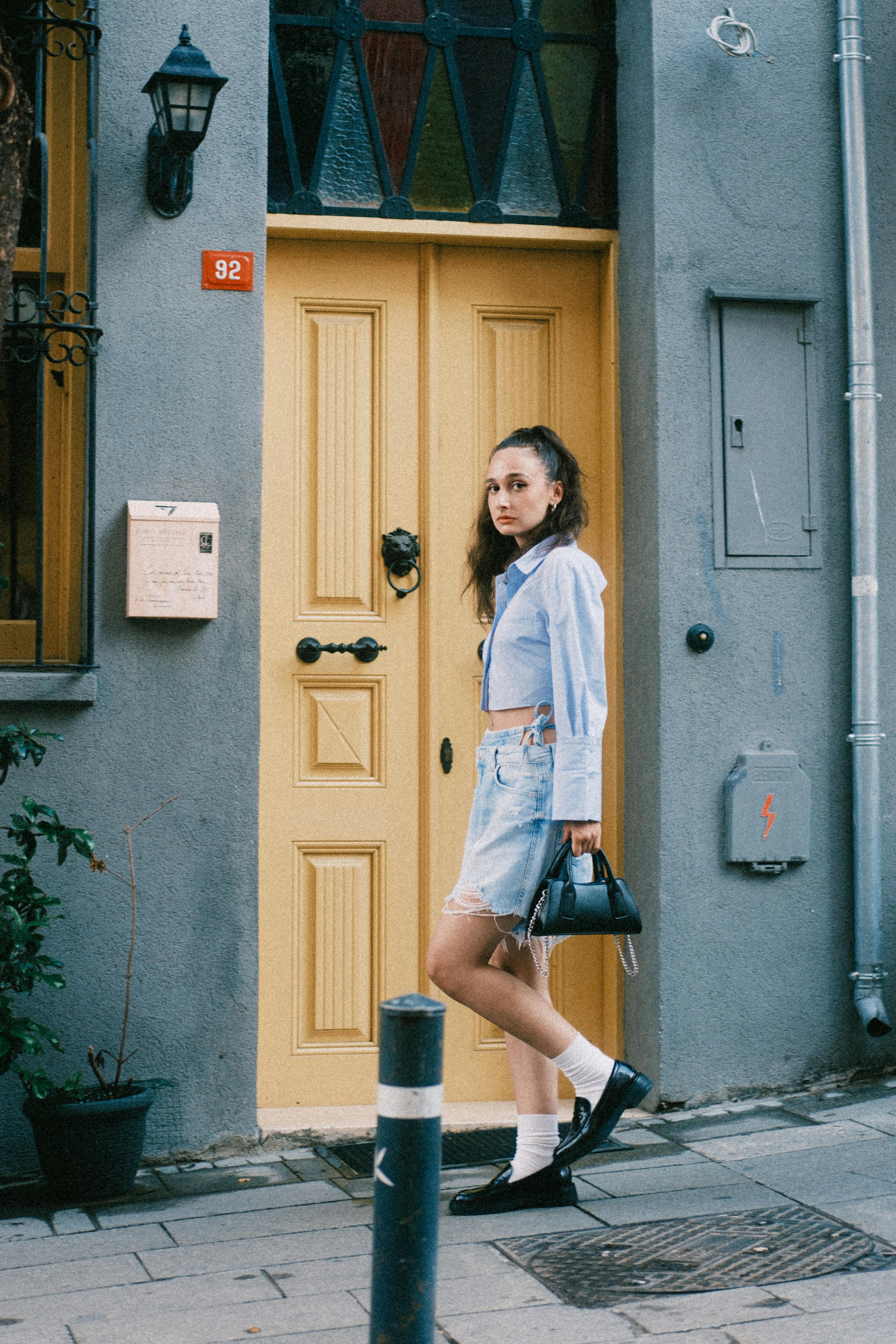 Stylish woman posing in urban area with yellow door.