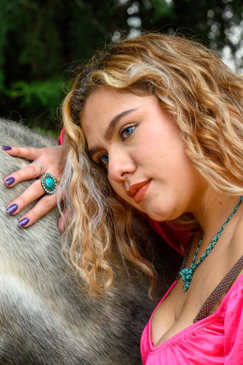 Free Portrait of a young woman with wavy hair, embracing an animal outdoors. Stock Photo