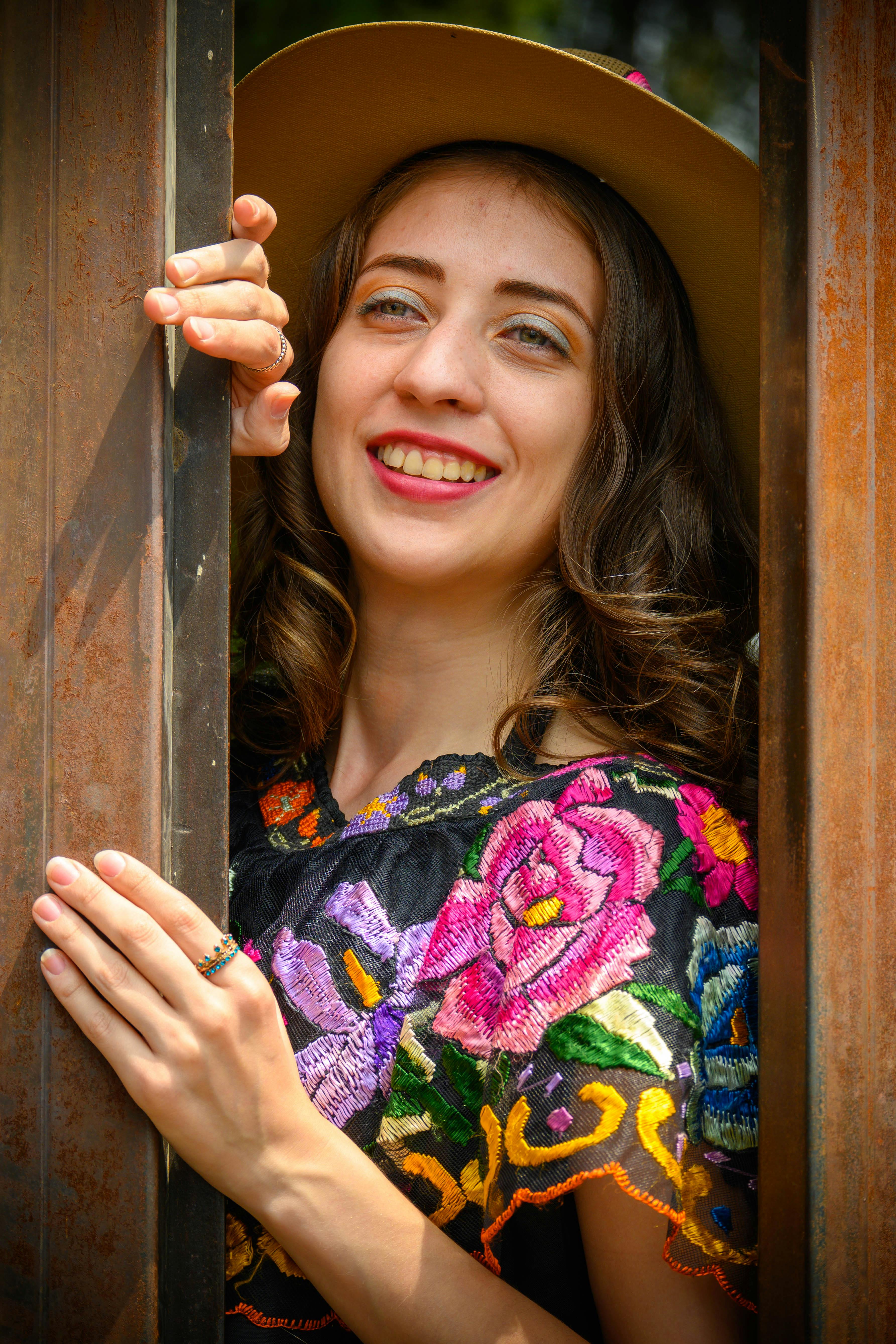 a woman in a hat and dress leaning against a wooden door