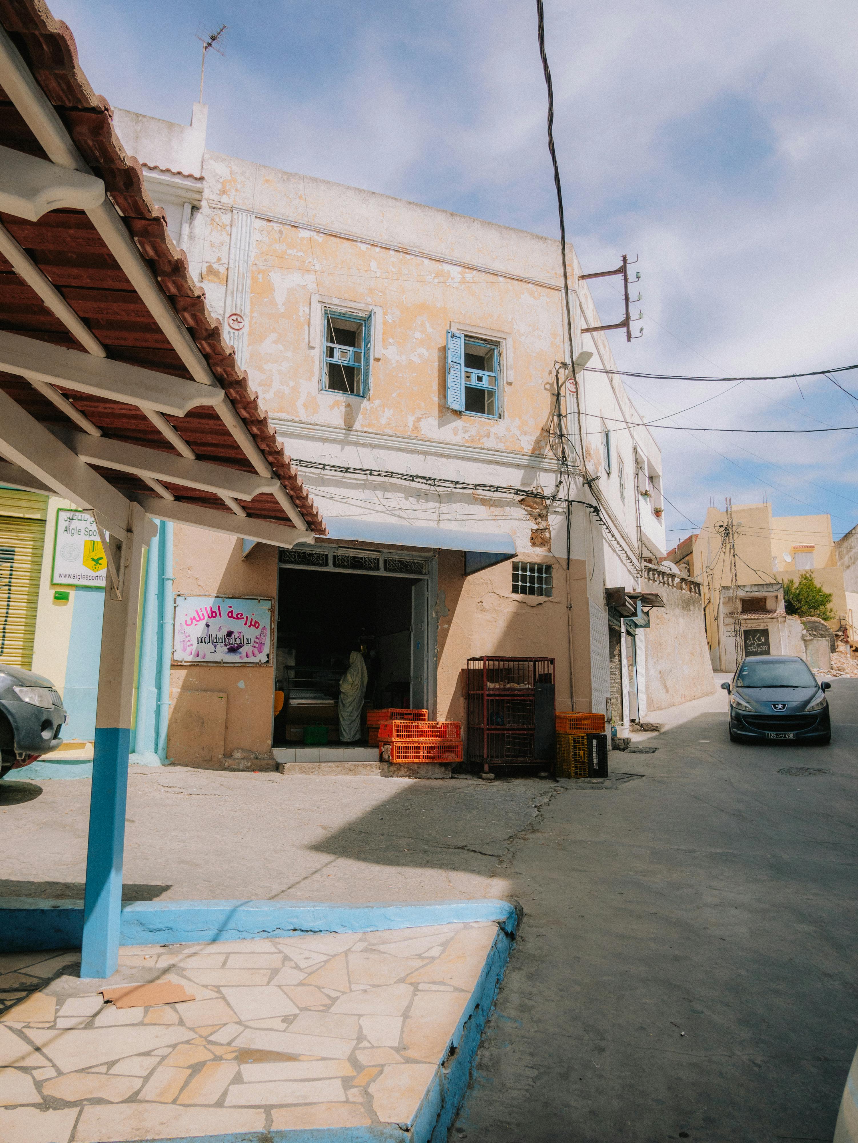 a street with a blue car parked in front of a building