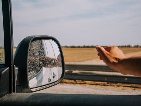 A scenic drive captured with a hand reaching out of a car window, perfect for travel themes.