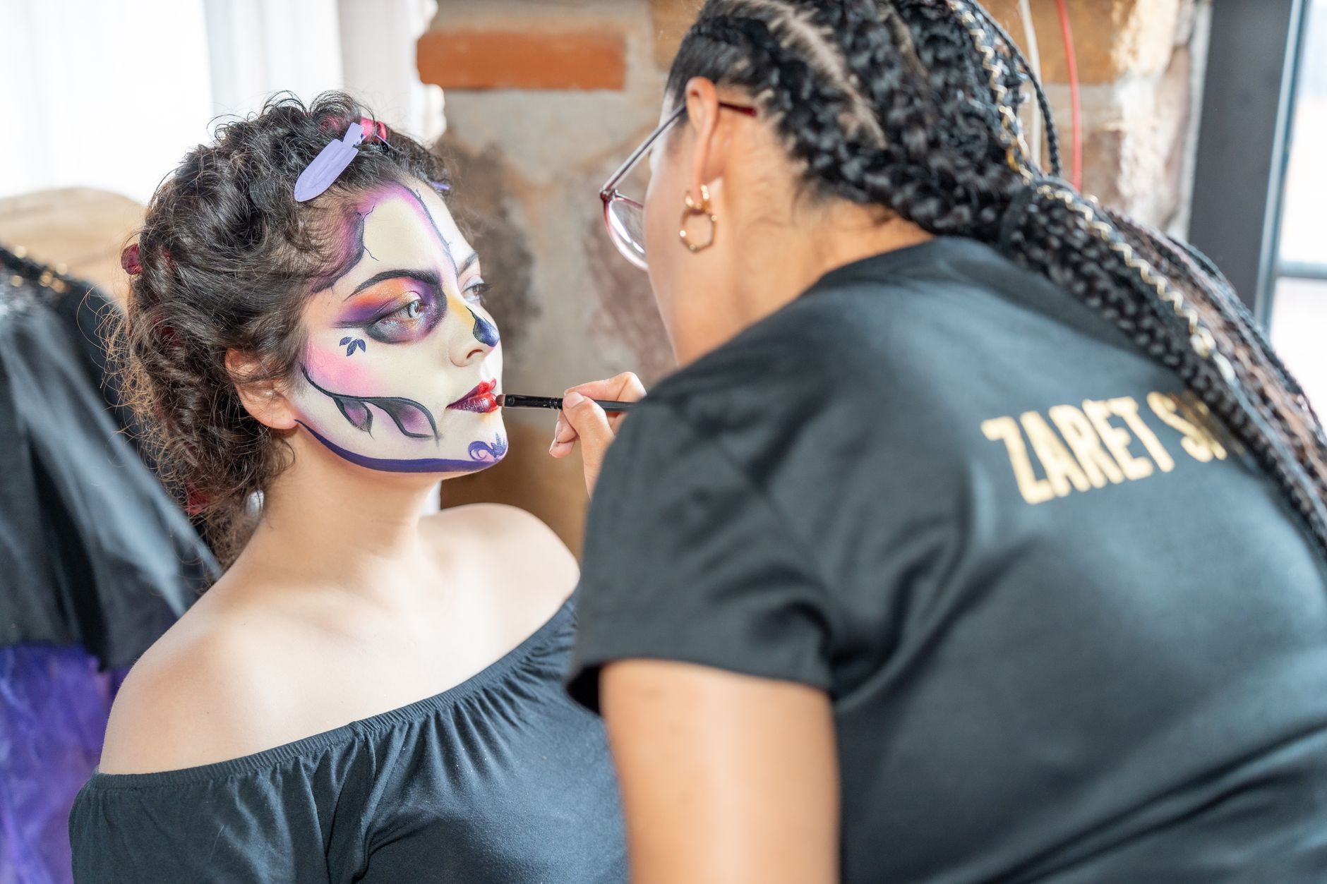 face painting artist cairo — A makeup artist applies intricate Day of the Dead face paint to a woman in Mexico City.