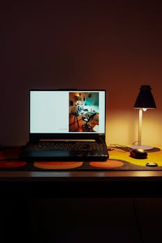 A cozy home workspace with a laptop, desk lamp, and warm ambient lighting, perfect for productivity.
