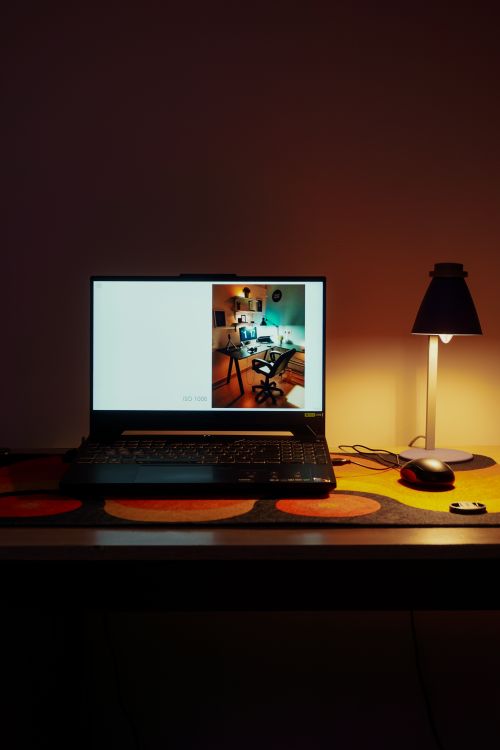 Free A cozy home workspace with a laptop, desk lamp, and warm ambient lighting, perfect for productivity. Stock Photo