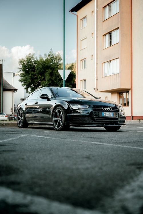 Free A stylish black sports car parked on a city street with buildings in the background. Stock Photo
