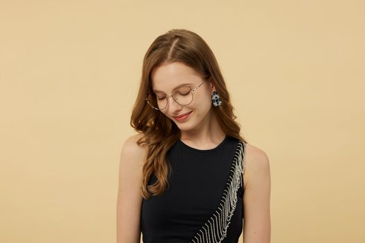 Young woman with glasses posing elegantly against a neutral background.