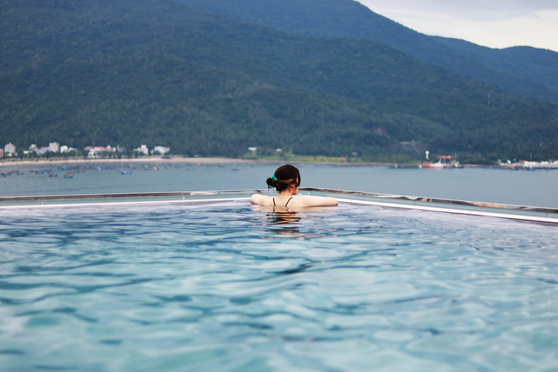 Woman enjoying a peaceful swim in an infinity pool with scenic Da Nang views.