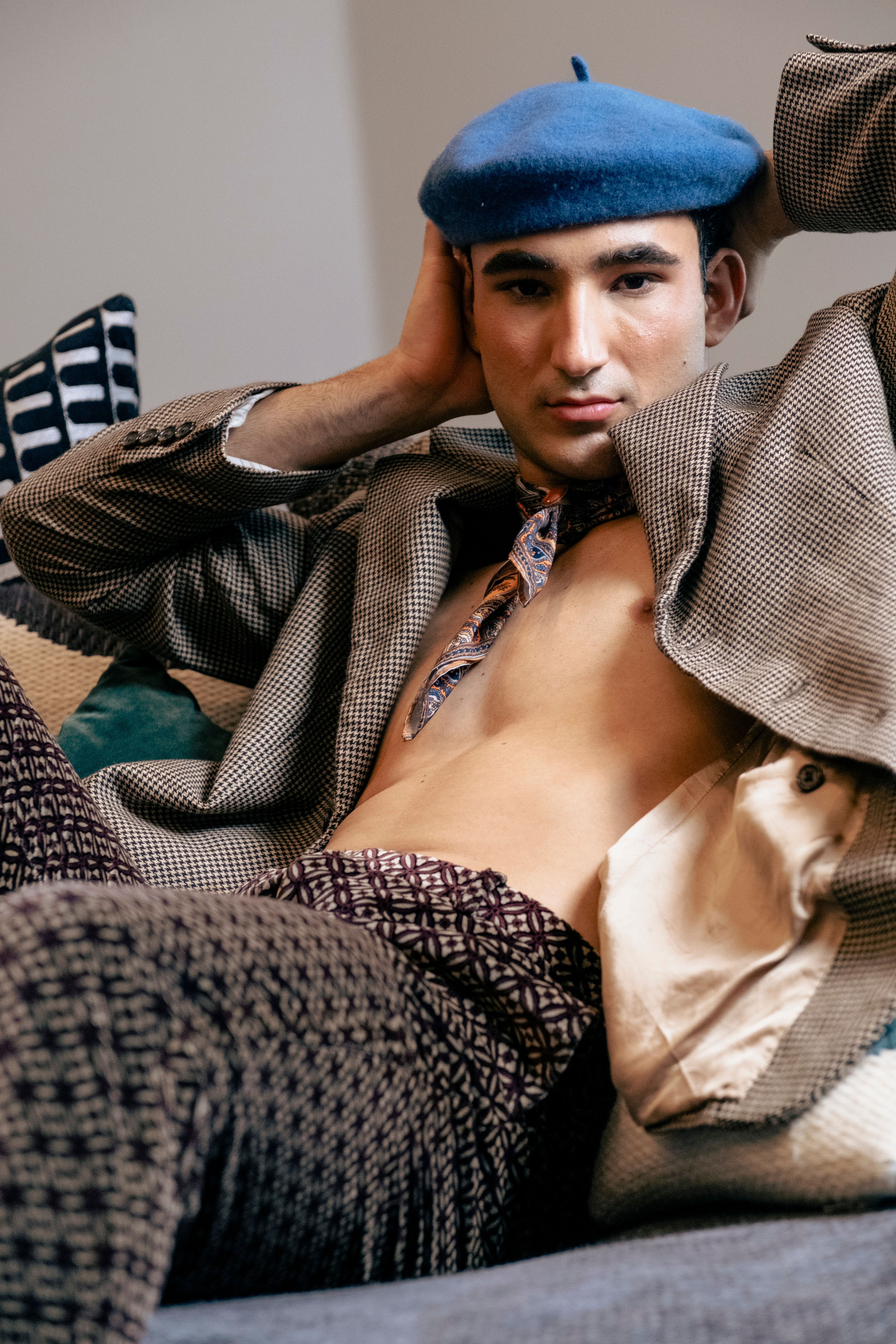 Young male model wearing a blue beret and vintage attire, posing indoors.