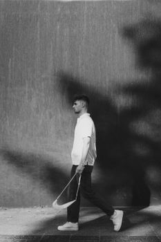 Black and white photo of a man walking on city streets, casting a shadow.