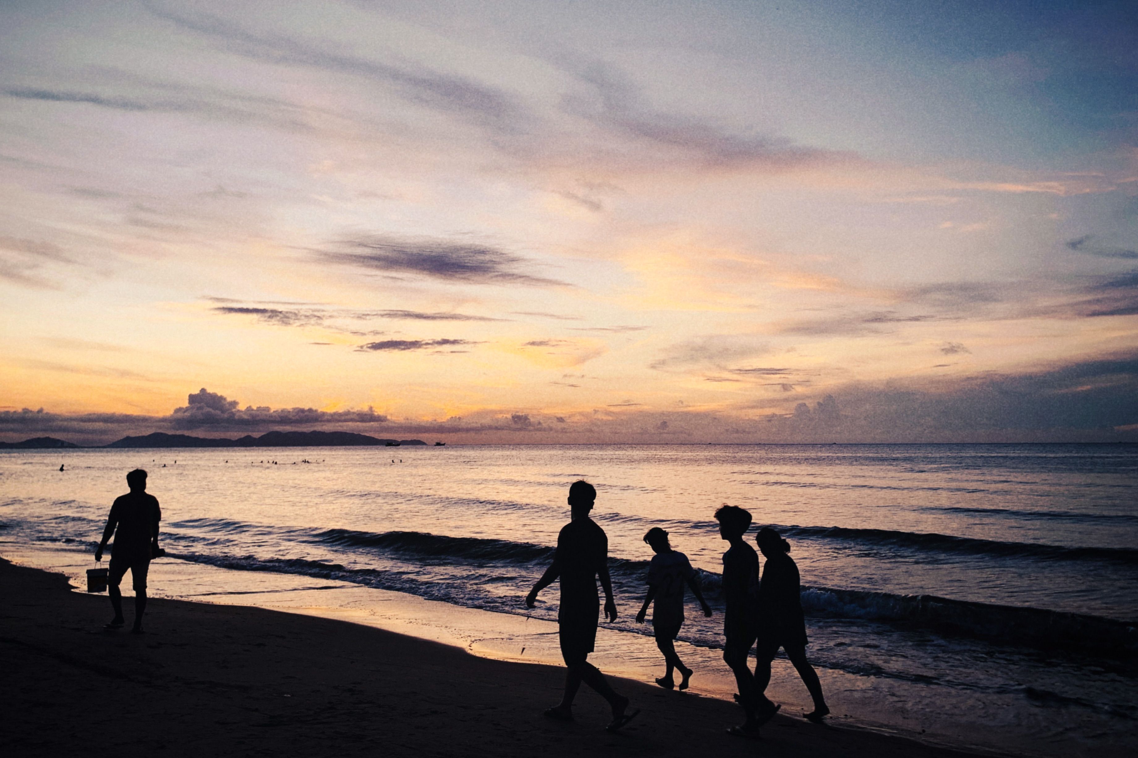 Silhouette Of People Walking On Seashore During Sunset · Free Stock Photo