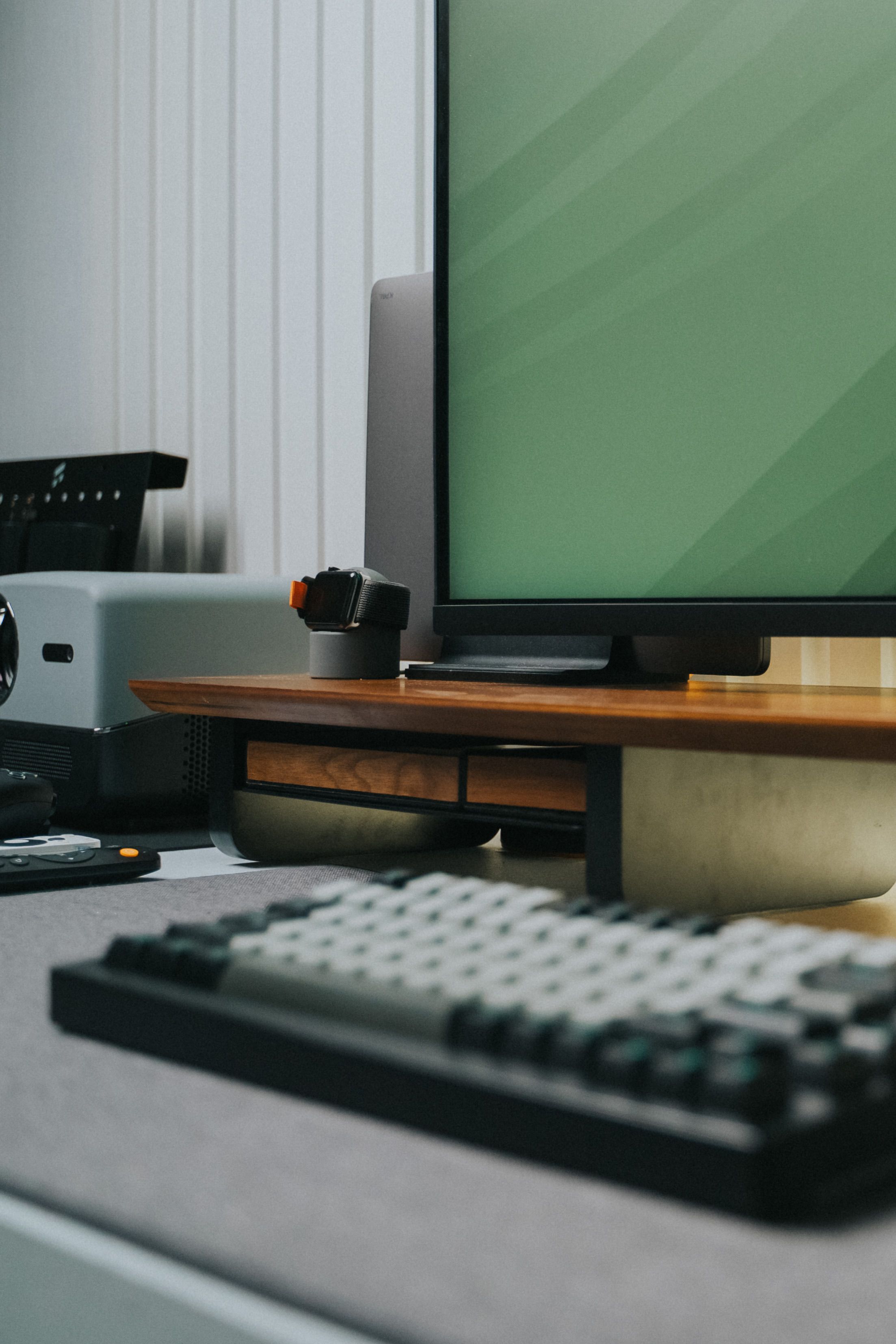 A contemporary office desk setup with keyboard, monitor, and tech accessories.
