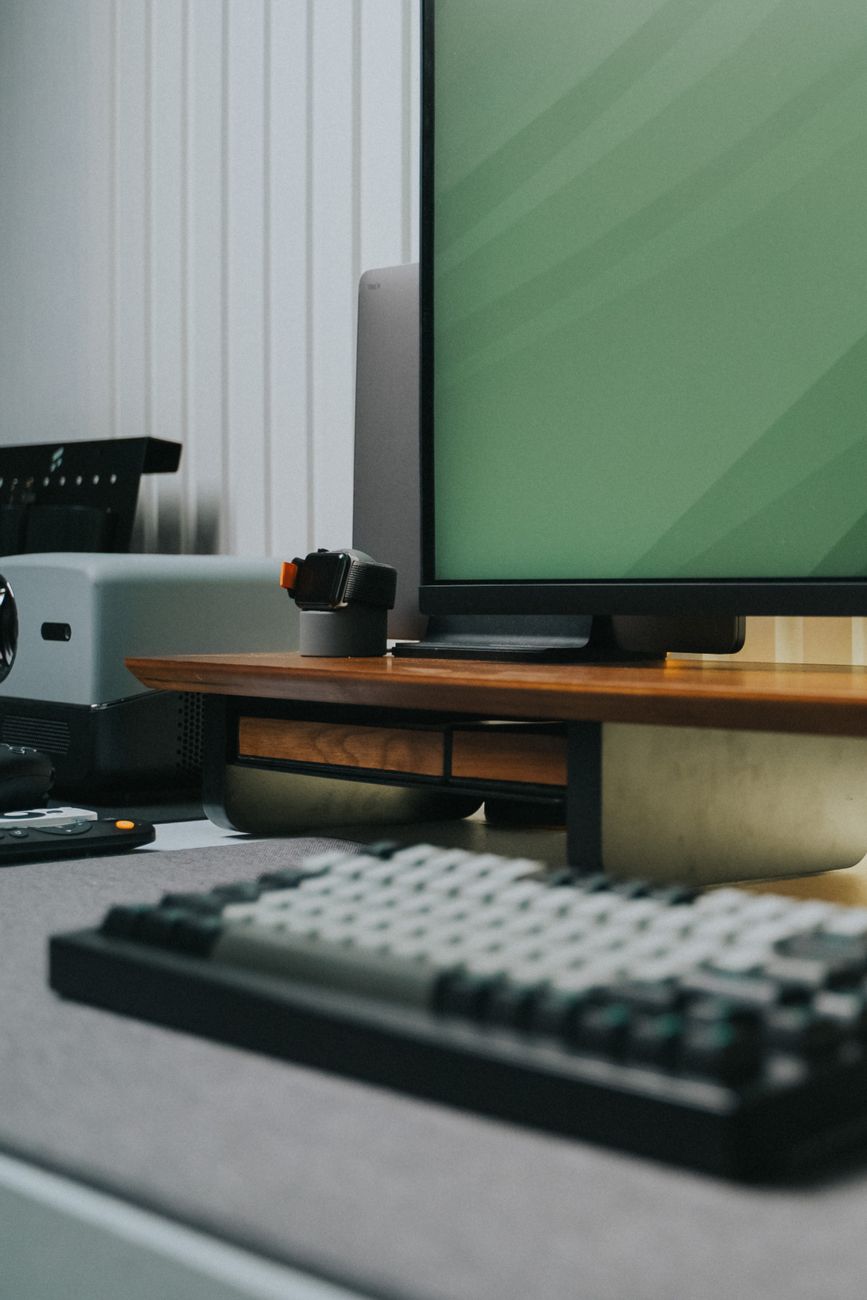 A contemporary office desk setup with keyboard, monitor, and tech accessories.