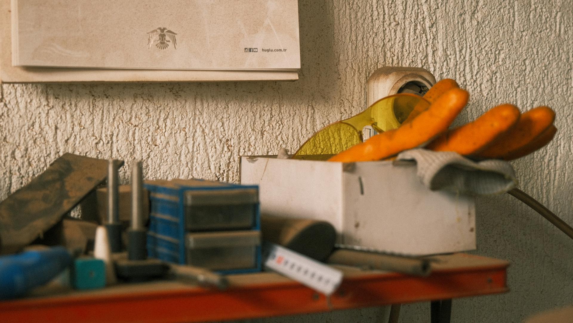 An organized workshop bench with tools, gloves, and storage boxes in a retro setting.