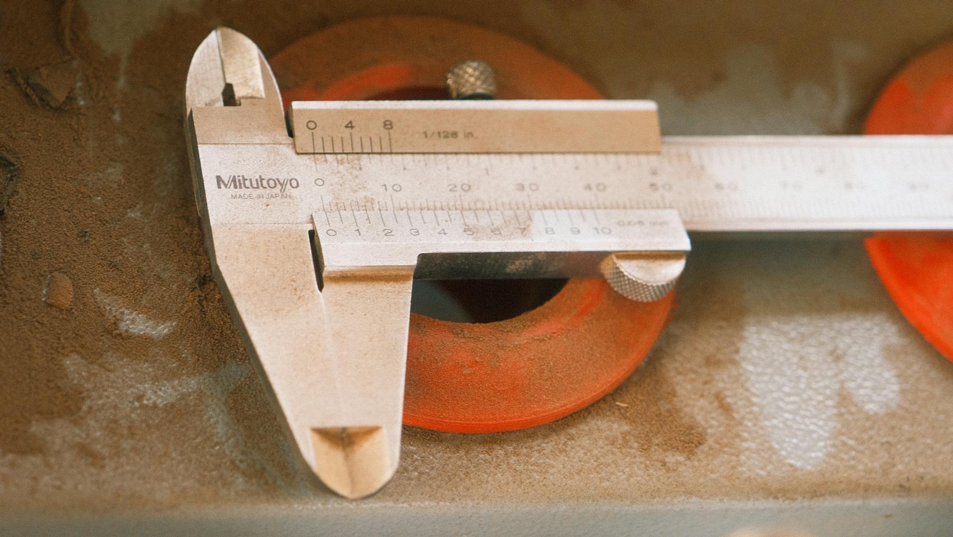 A precision vernier caliper measuring tool on a dusty industrial surface.