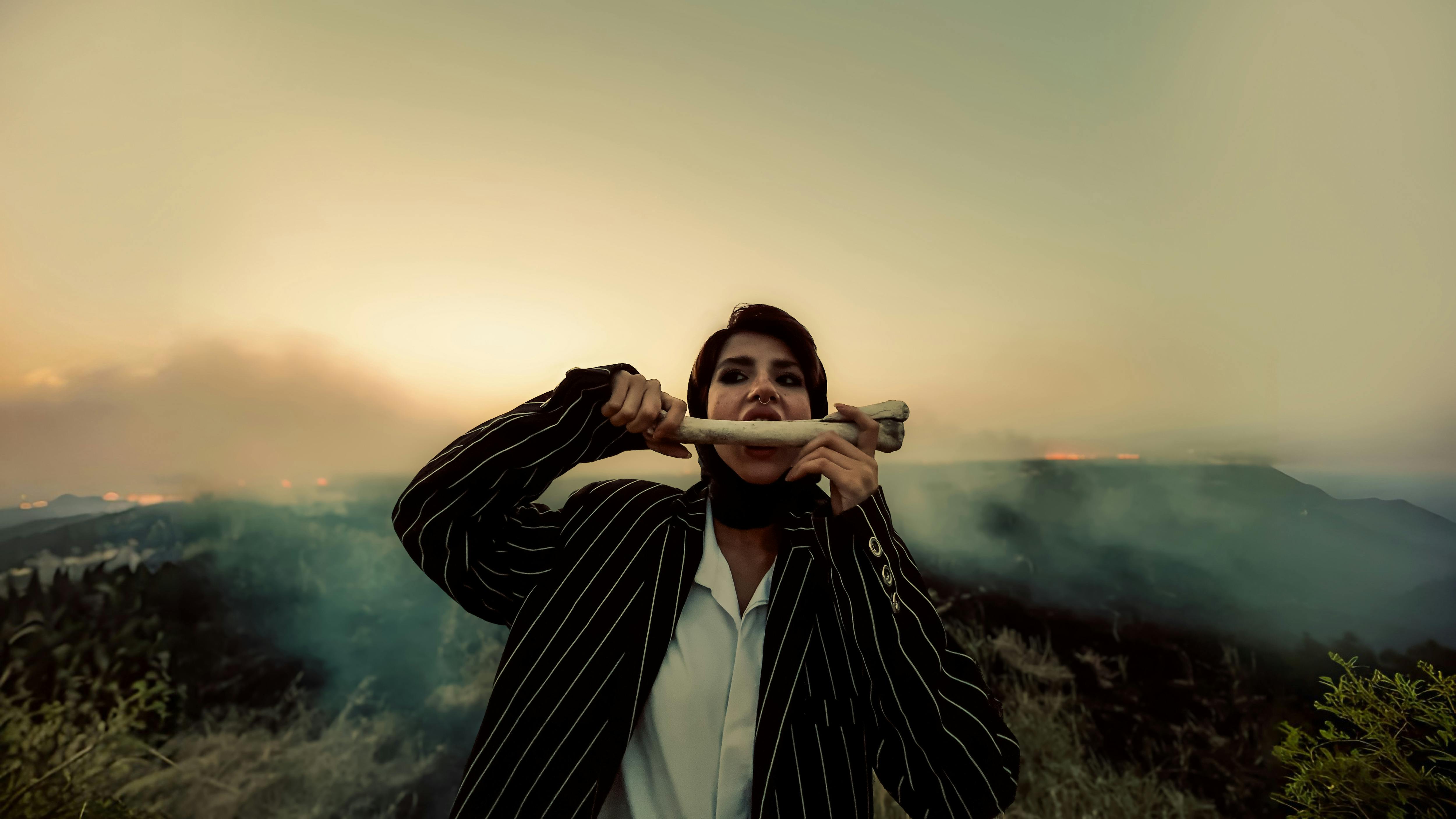 a man in a suit holding a cigarette in front of a mountain