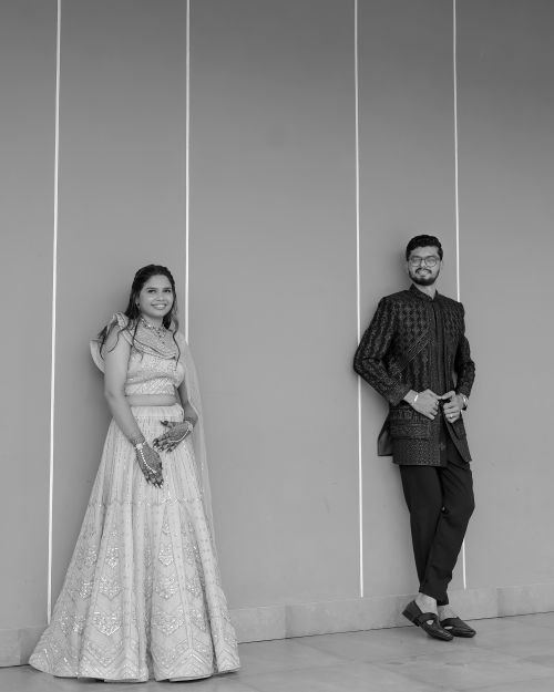Free Black and white photo of a couple in traditional attire, leaning against a wall, at a wedding. Stock Photo