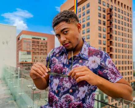 Stylish young man posing on a rooftop in Mexico City with urban buildings in the background.