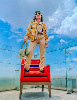 Stylish woman stands confidently on rooftop with city view, showcasing vibrant fashion.