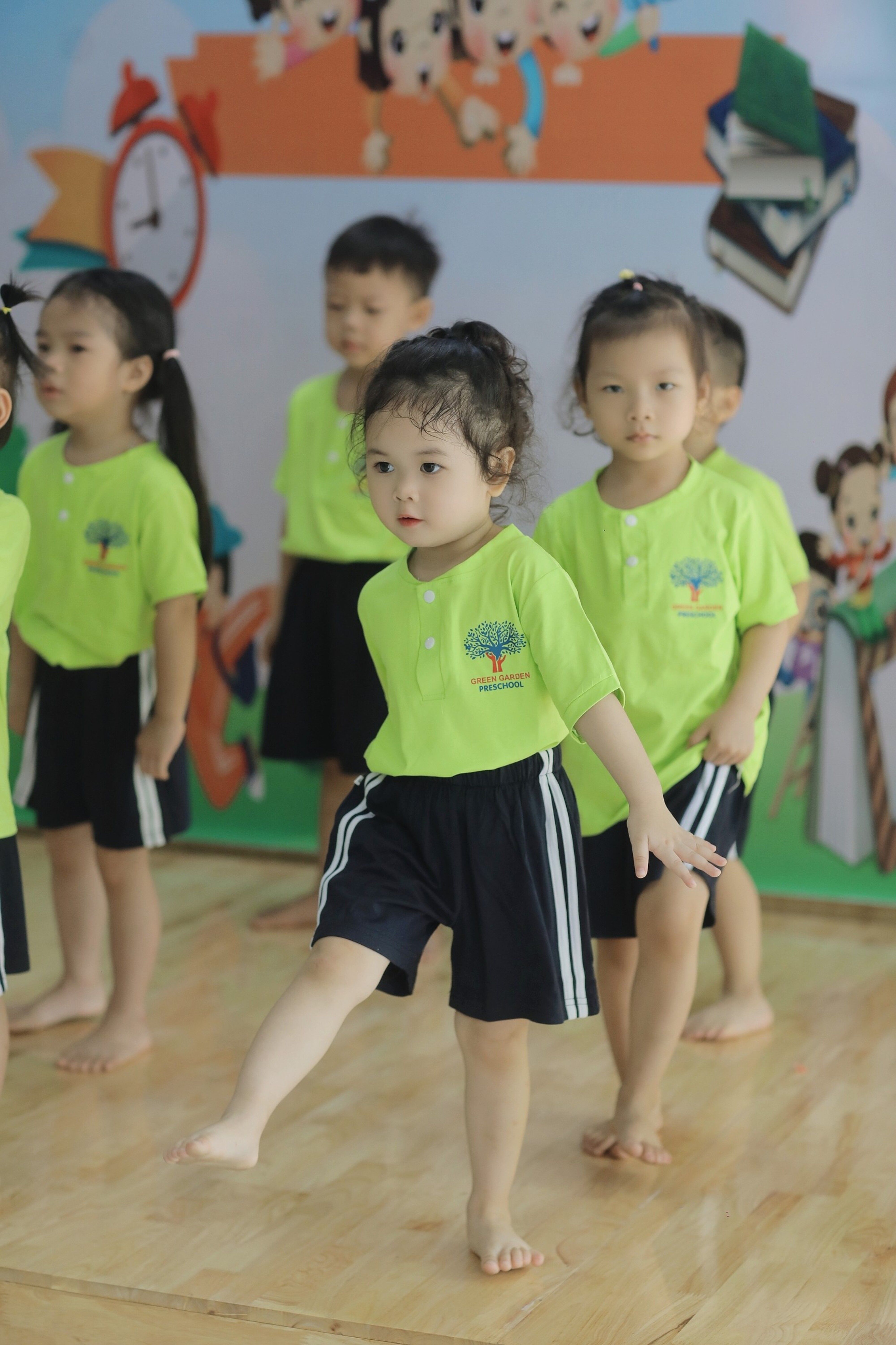 Group of young children engaging in a fun indoor dance activity at school.