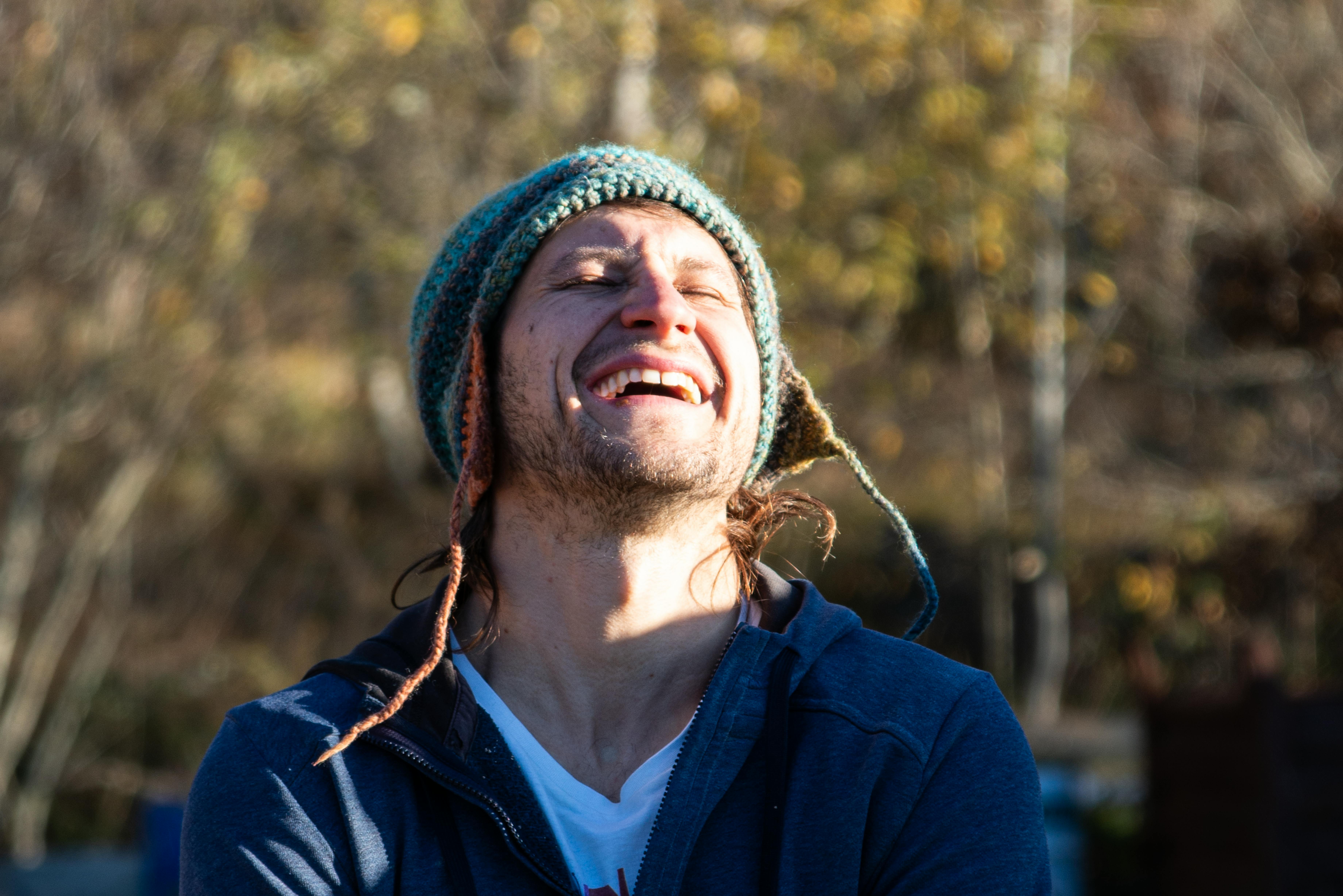 a man with dreadlocks laughing while wearing a beanie