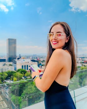 Smiling woman enjoying a sunny day on a Mexico City rooftop with a scenic view.