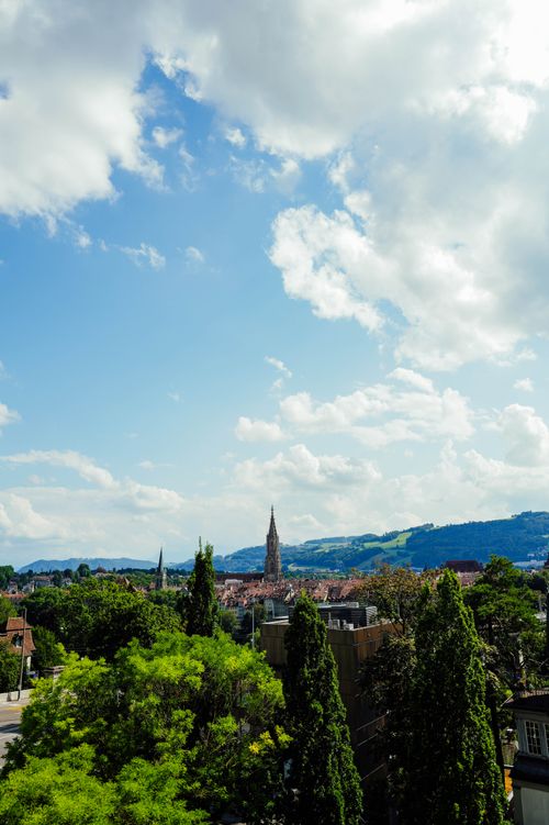 Free A picturesque city skyline featuring a gothic church tower under a bright blue sky. Stock Photo