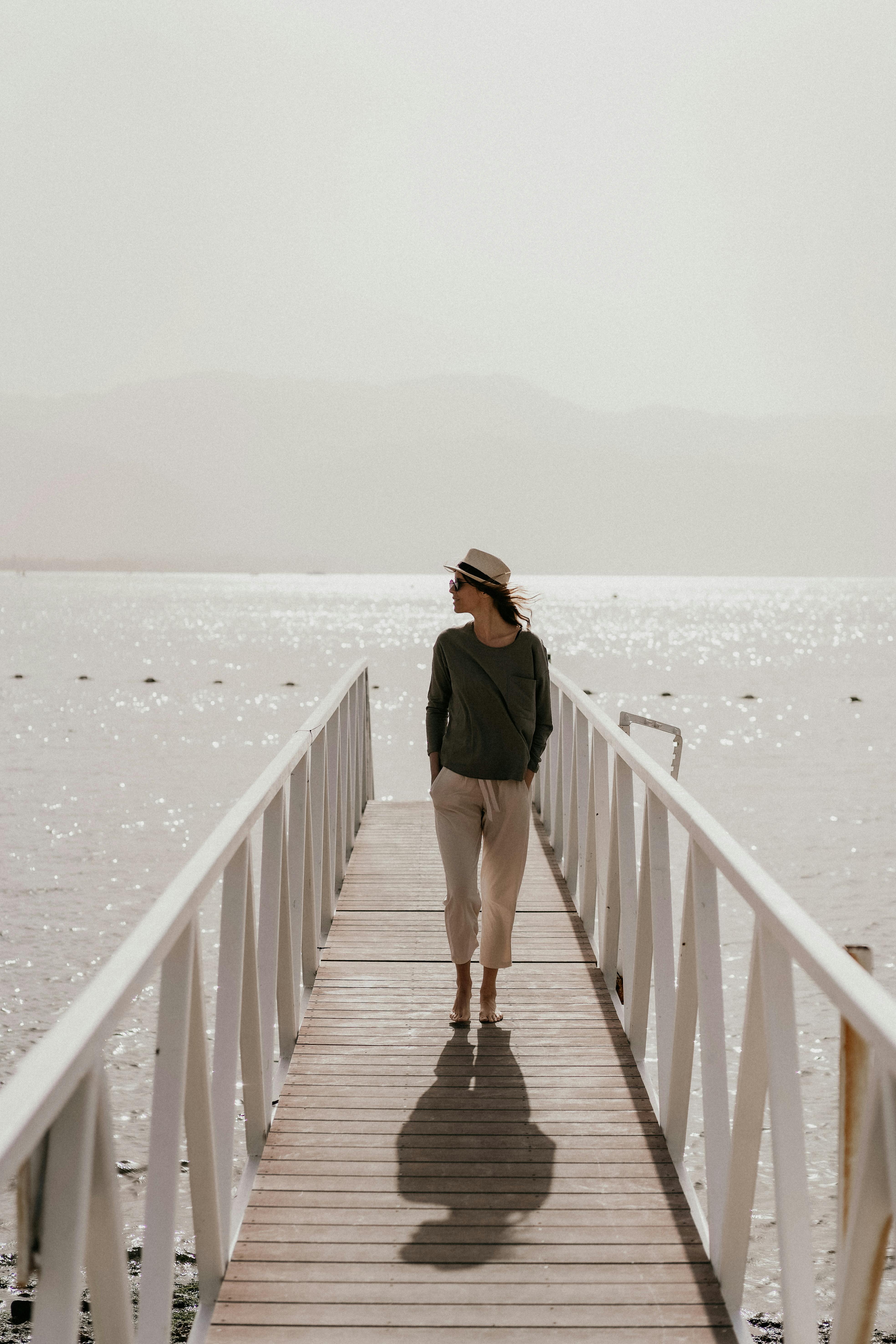 Woman strolling on a sunlit boardwalk in Eilat, Israel, by the Red Sea.