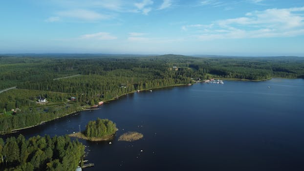 Drone shot showcasing a serene Finnish lake surrounded by lush forests.