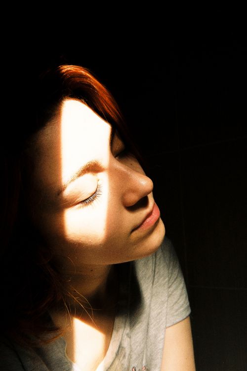 Free A serene portrait of a woman bathed in sunlight with closed eyes, evoking calmness. Stock Photo