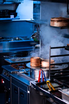 A bustling commercial kitchen with steaming bamboo steamers on an industrial stove.