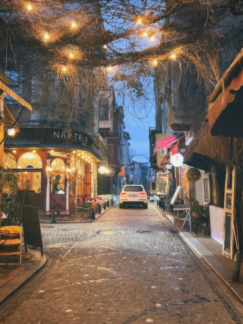 Free A cozy evening setting of a beautifully lit narrow alley with quaint cafes. Stock Photo