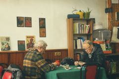 Two senior men playing cards in a cozy room with vintage decor and warm lighting.