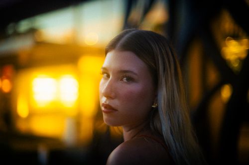 Free Captivating portrait of a young woman with a bokeh-lit urban background, exuding elegance and mystery. Stock Photo
