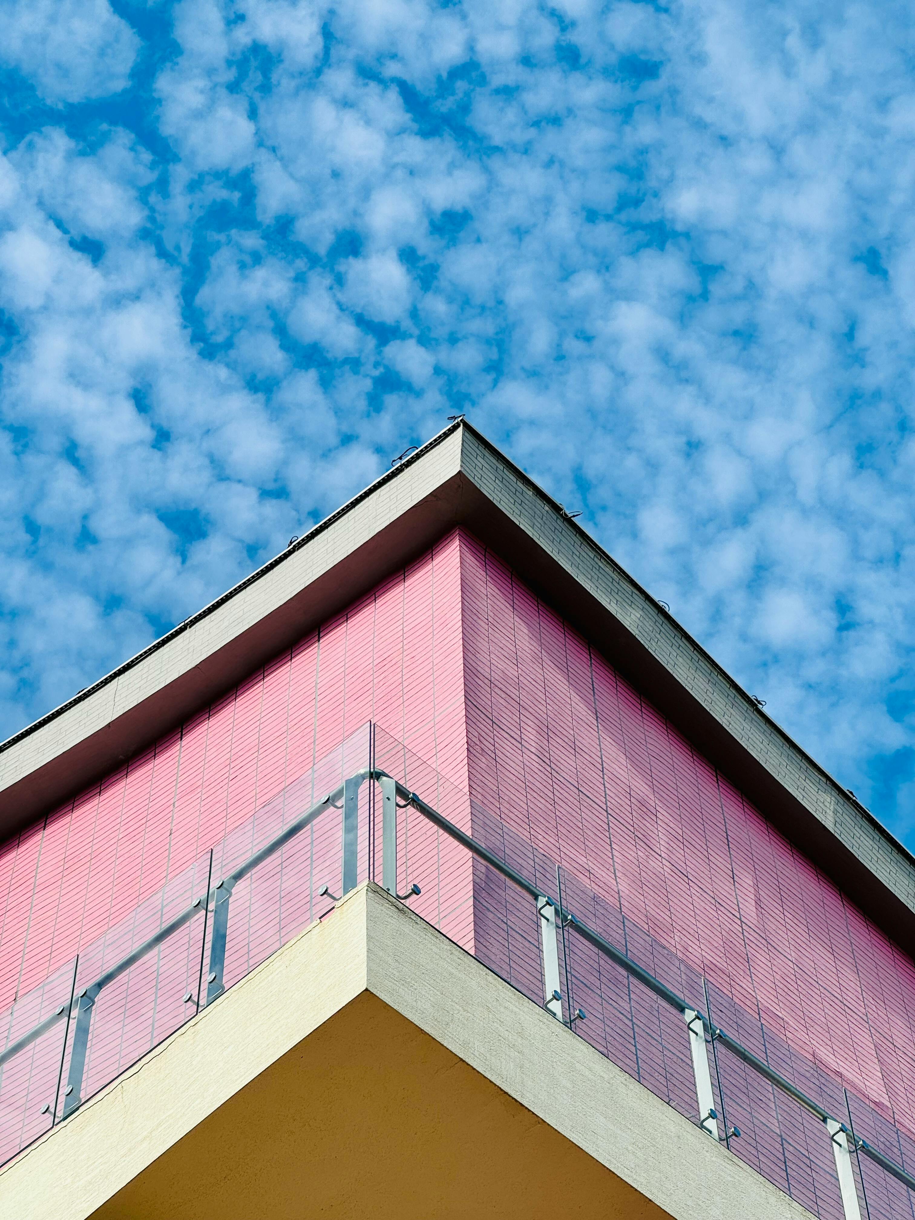 a pink building with a balcony and a blue sky