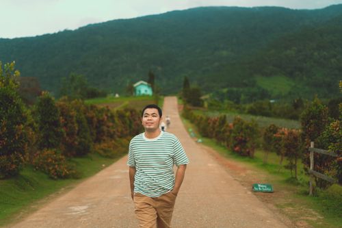 Free A man strolls along a scenic road in Dalat, surrounded by lush greenery and mountains. Stock Photo