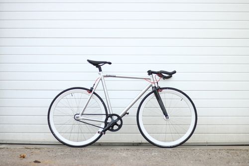 Free A sleek bicycle parked upright against a white garage door, showcasing a minimalist style. Stock Photo