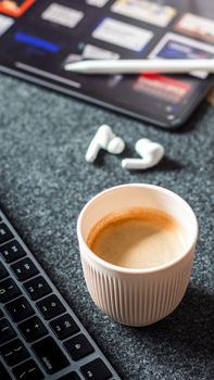 A cozy setup with coffee, laptop, and earbuds ready for work or study.